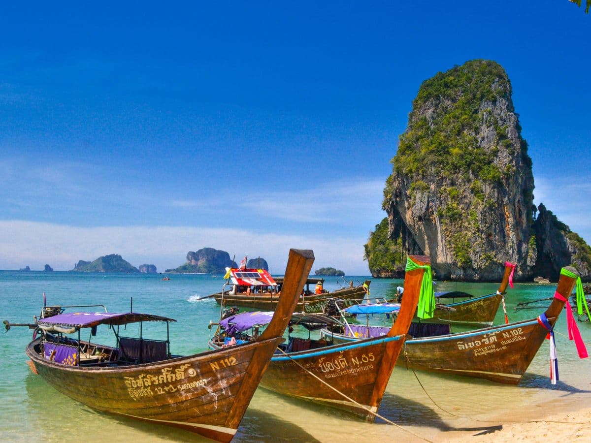 Longtail boats moored by limestone cliffs in Thailand